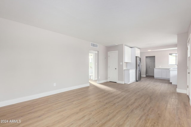 unfurnished living room with light wood-style flooring, baseboards, and visible vents