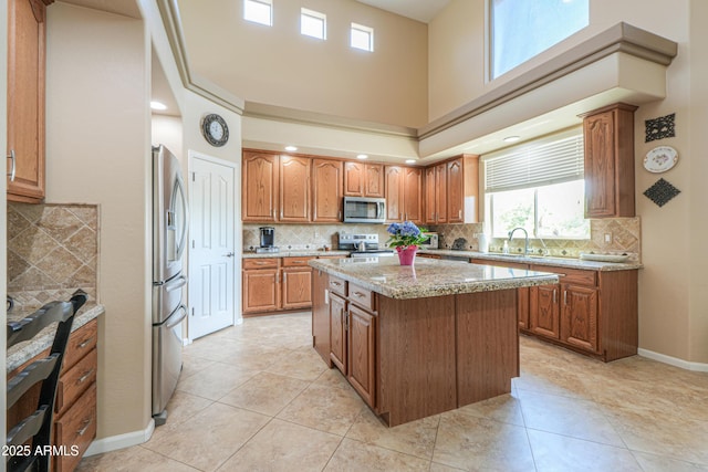 21841 N Ingram Ct, Maricopa, AZ 85138 - kitchen featuring appliances with stainless steel finishes, a sink, a kitchen island, tasteful backsplash, and brown cabinets