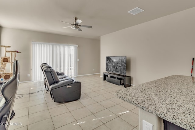 living room featuring light tile patterned flooring, visible vents, ceiling fan, and baseboards