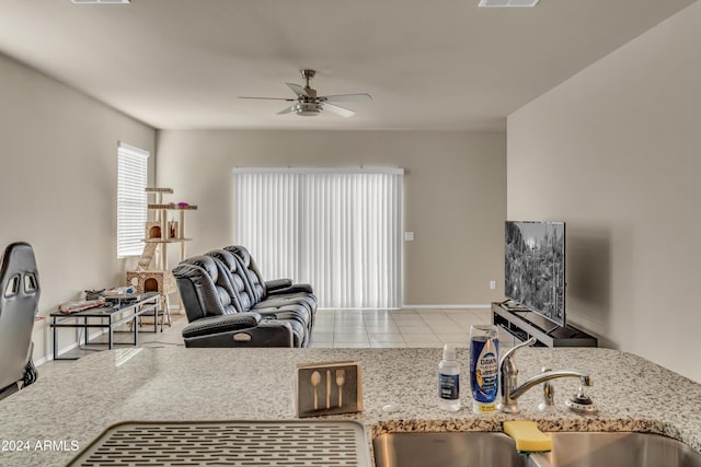 tiled living room with a sink, ceiling fan, visible vents, and baseboards