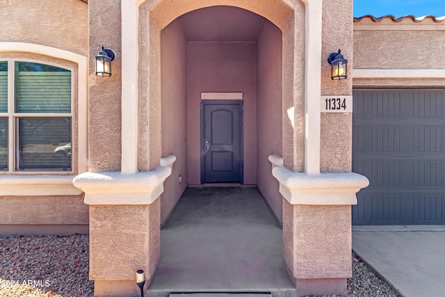 entrance to property featuring a garage and stucco siding
