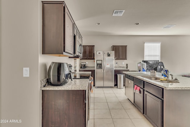 kitchen featuring a kitchen island with sink, light tile patterned floors, dark brown cabinetry, visible vents, and appliances with stainless steel finishes