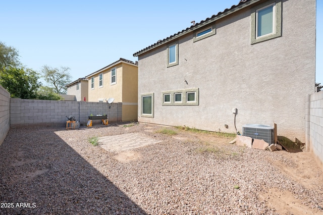 back of property with central AC unit, stucco siding, a tile roof, and a fenced backyard