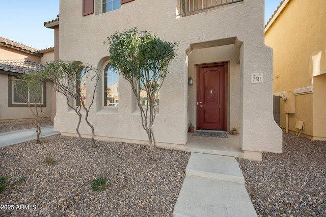 view of exterior entry featuring a tiled roof and stucco siding