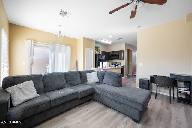 living room with visible vents, baseboards, light wood-style flooring, and ceiling fan with notable chandelier