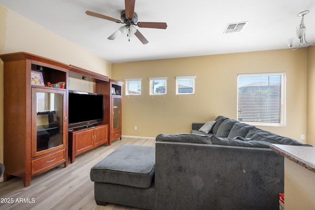 living area with a wealth of natural light, visible vents, light wood-style floors, and ceiling fan