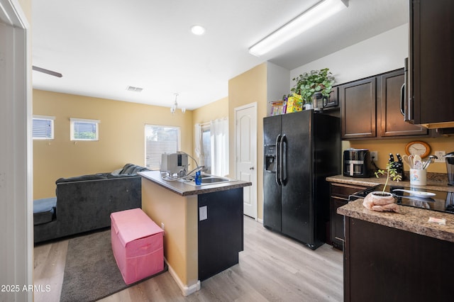 kitchen with a sink, plenty of natural light, open floor plan, and black fridge