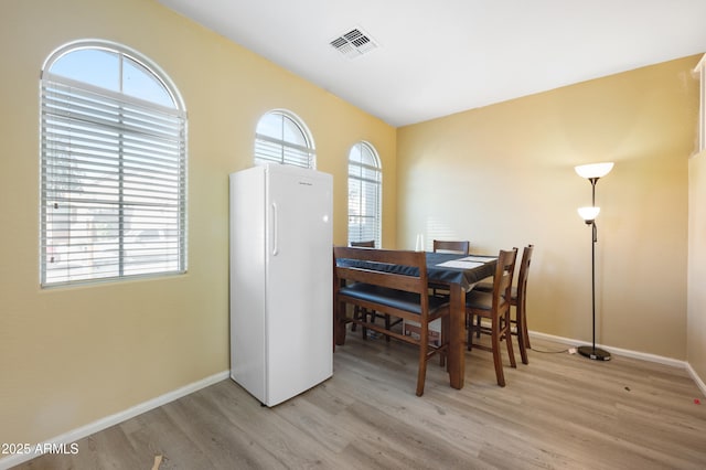 dining room with visible vents, plenty of natural light, baseboards, and light wood-style flooring