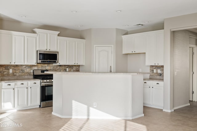 kitchen featuring backsplash, a center island with sink, white cabinets, light tile patterned flooring, and stainless steel appliances