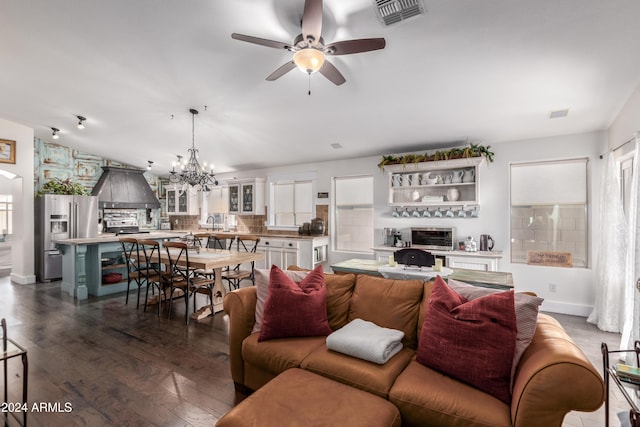 living room with visible vents, dark wood finished floors, baseboards, and ceiling fan with notable chandelier