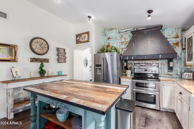 kitchen with a center island, appliances with stainless steel finishes, white cabinetry, wood counters, and exhaust hood