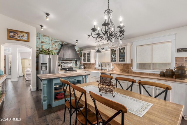 kitchen with lofted ceiling, white cabinetry, appliances with stainless steel finishes, glass insert cabinets, and pendant lighting