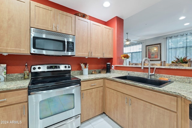 kitchen with light stone countertops, sink, appliances with stainless steel finishes, and light tile patterned flooring