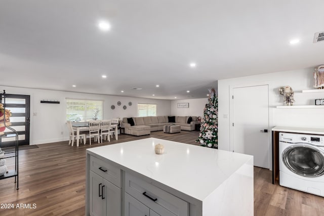 kitchen featuring gray cabinets, dark hardwood / wood-style flooring, a kitchen island, and washer / dryer