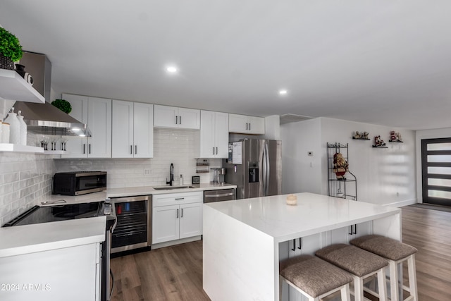 kitchen featuring white cabinets, stainless steel appliances, beverage cooler, and sink