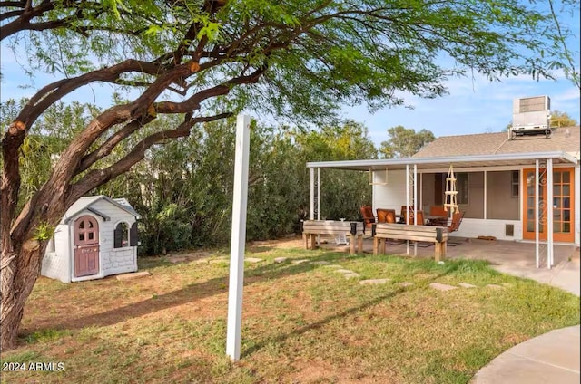 view of yard featuring central AC unit, a patio area, and a sunroom