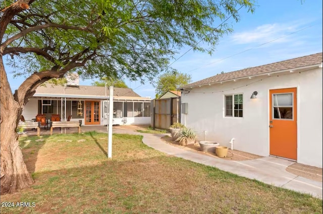 rear view of house with a lawn, a patio area, and a sunroom