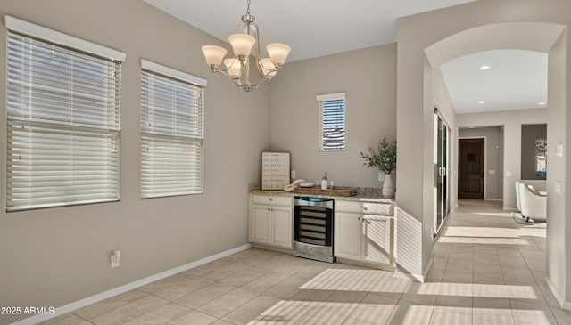 4341 E Evelyn St, Gilbert, AZ 85295 - indoor bar featuring beverage cooler, light tile patterned floors, a chandelier, arched walkways, and hanging light fixtures