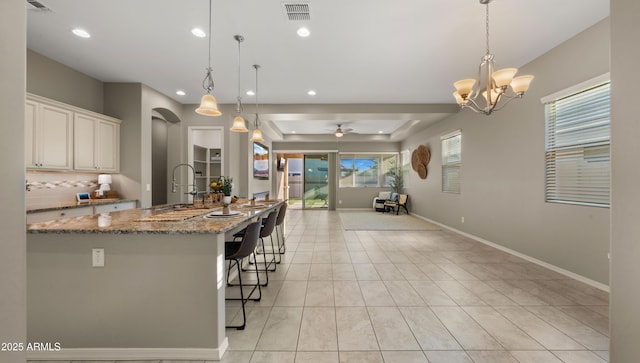 4341 E Evelyn St, Gilbert, AZ 85295 - kitchen with open floor plan, recessed lighting, backsplash, light stone counters, and a kitchen bar