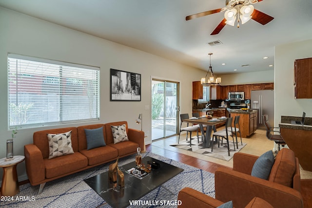 living room with a healthy amount of sunlight, sink, ceiling fan with notable chandelier, and light wood-type flooring