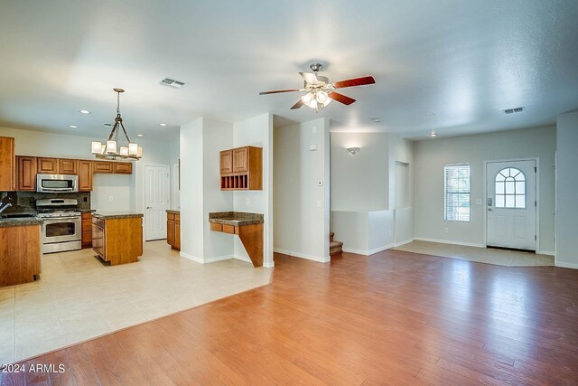 kitchen featuring a center island, light hardwood / wood-style flooring, decorative light fixtures, ceiling fan with notable chandelier, and appliances with stainless steel finishes