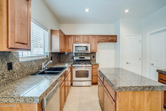 kitchen with a kitchen island, stainless steel appliances, sink, and backsplash