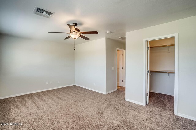 interior space featuring a walk in closet, ceiling fan, a closet, and carpet floors