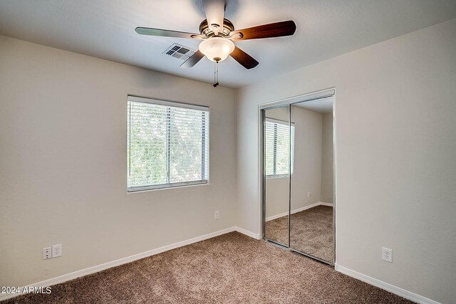 unfurnished bedroom featuring ceiling fan, a closet, carpet floors, and multiple windows