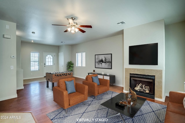 living room with a tiled fireplace, hardwood / wood-style flooring, and ceiling fan