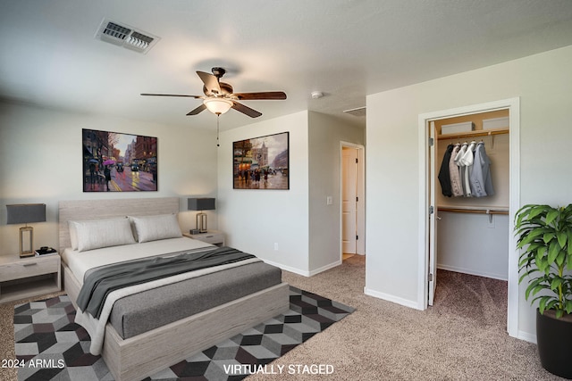 bedroom with light carpet, a walk in closet, ceiling fan, and a closet