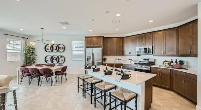 23113 E Saddle Way, Queen Creek, AZ 85142 - kitchen with appliances with stainless steel finishes, a breakfast bar area, light countertops, a center island with sink, and dark brown cabinets