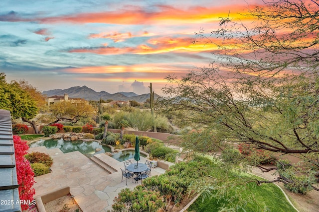 exterior space featuring a jacuzzi, a mountain view, and a patio area