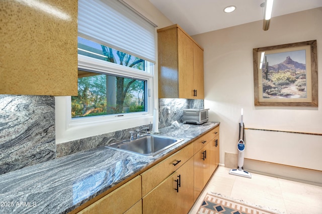 kitchen featuring sink, dark stone countertops, light brown cabinets, and light tile patterned floors