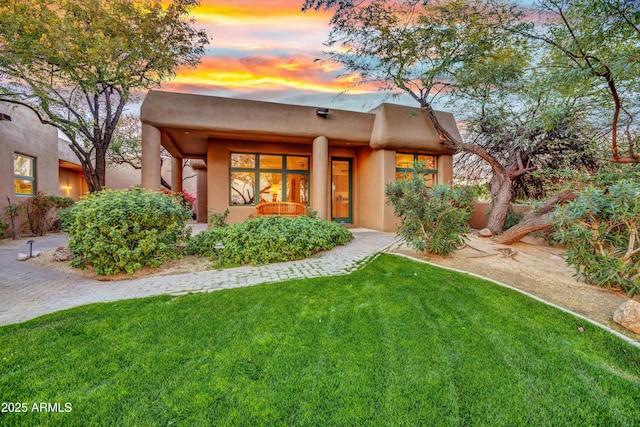 pueblo-style home featuring a lawn