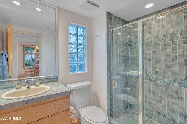 bathroom with vanity, a shower with door, and toilet