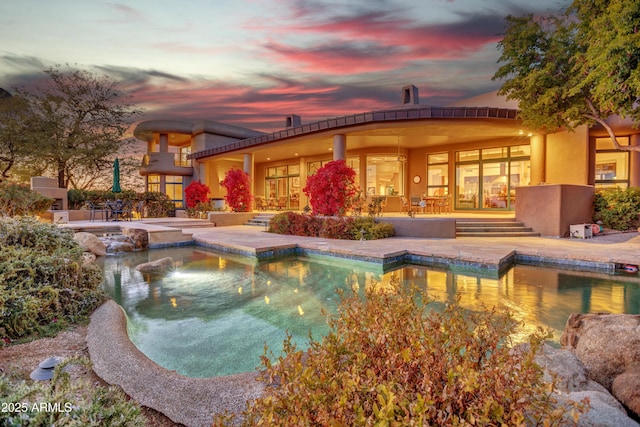 pool at dusk featuring a patio area