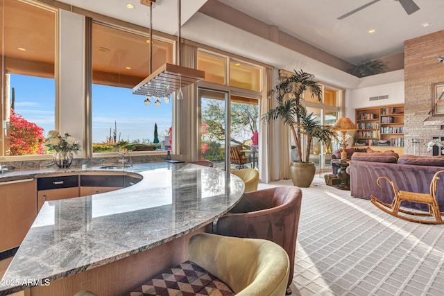 kitchen with stone countertops, sink, ceiling fan, and decorative light fixtures