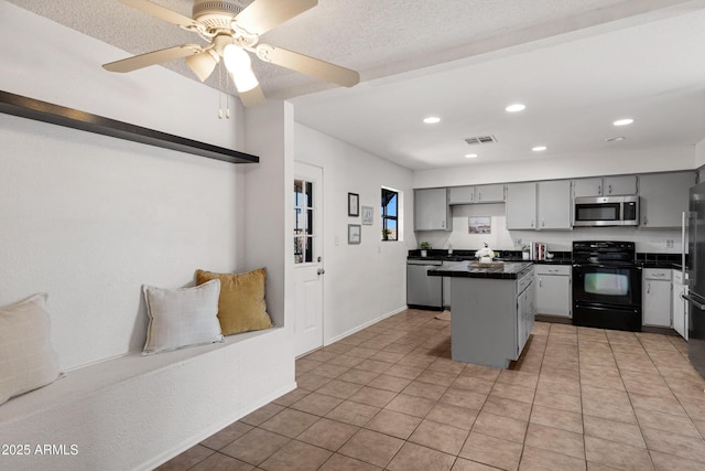 kitchen featuring a center island, light tile patterned floors, gray cabinets, ceiling fan, and black appliances