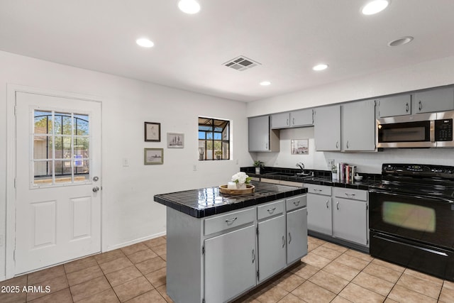 kitchen with gray cabinets, sink, a center island, tile counters, and black electric range