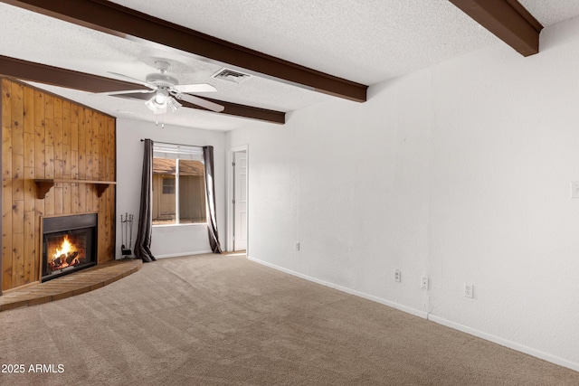 unfurnished living room with beamed ceiling, ceiling fan, light colored carpet, and a textured ceiling