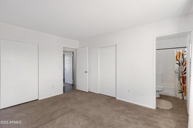 unfurnished bedroom with connected bathroom, carpet floors, and a textured ceiling