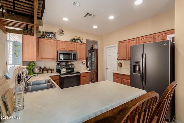 kitchen featuring kitchen peninsula, appliances with stainless steel finishes, a kitchen bar, and sink