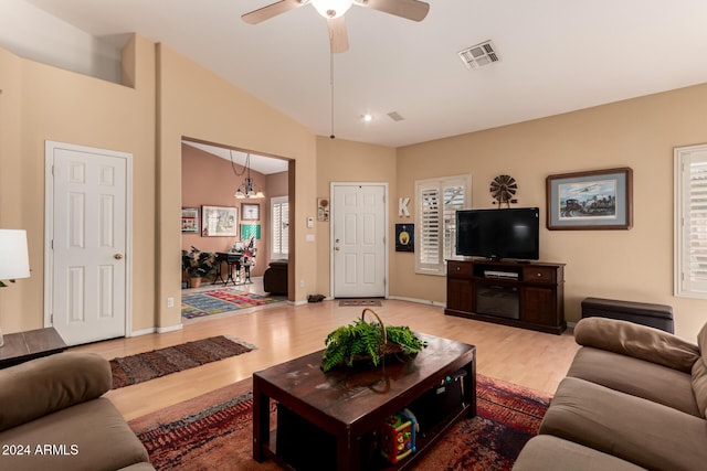 living room featuring ceiling fan with notable chandelier, lofted ceiling, light hardwood / wood-style floors, and a healthy amount of sunlight