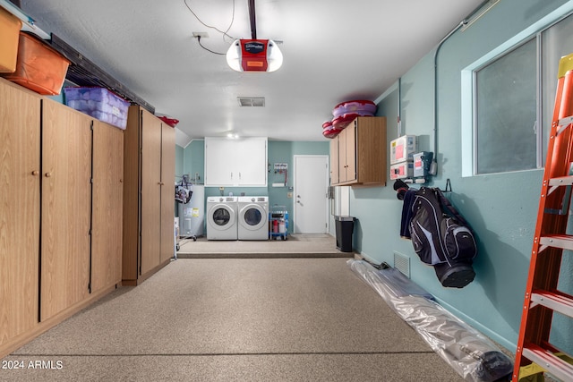 garage featuring electric water heater, a garage door opener, and independent washer and dryer