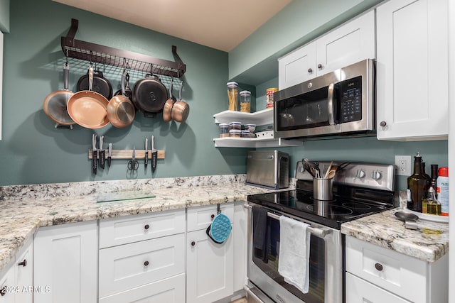 kitchen featuring light stone countertops, stainless steel appliances, and white cabinetry