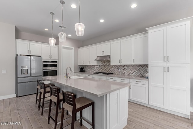 kitchen with pendant lighting, sink, appliances with stainless steel finishes, an island with sink, and white cabinets