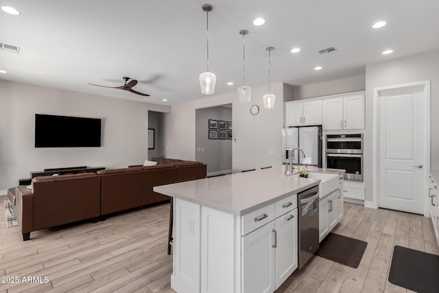 kitchen with stainless steel appliances, sink, an island with sink, and white cabinets