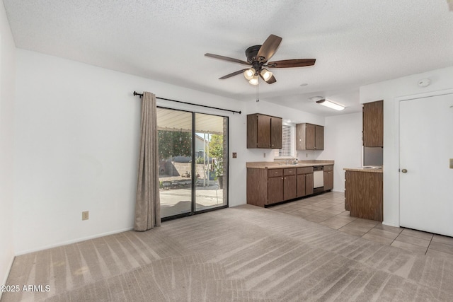 kitchen with a textured ceiling, dishwasher, sink, ceiling fan, and light colored carpet