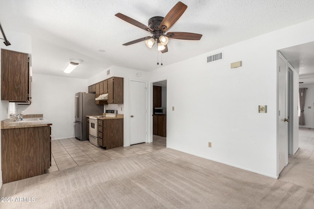 kitchen featuring a textured ceiling, white electric range oven, light carpet, sink, and high end refrigerator