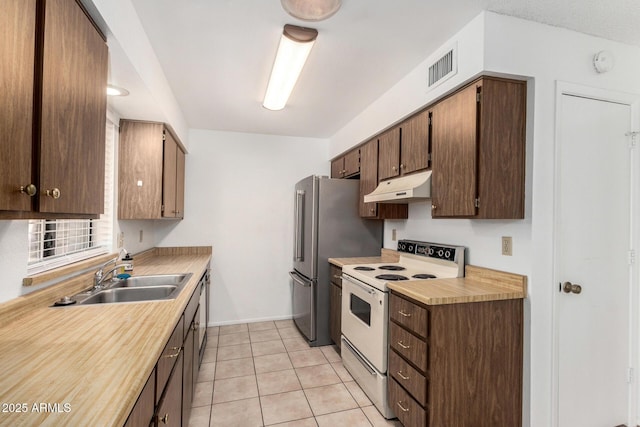 kitchen with sink, white range with electric stovetop, light tile patterned floors, and stainless steel fridge